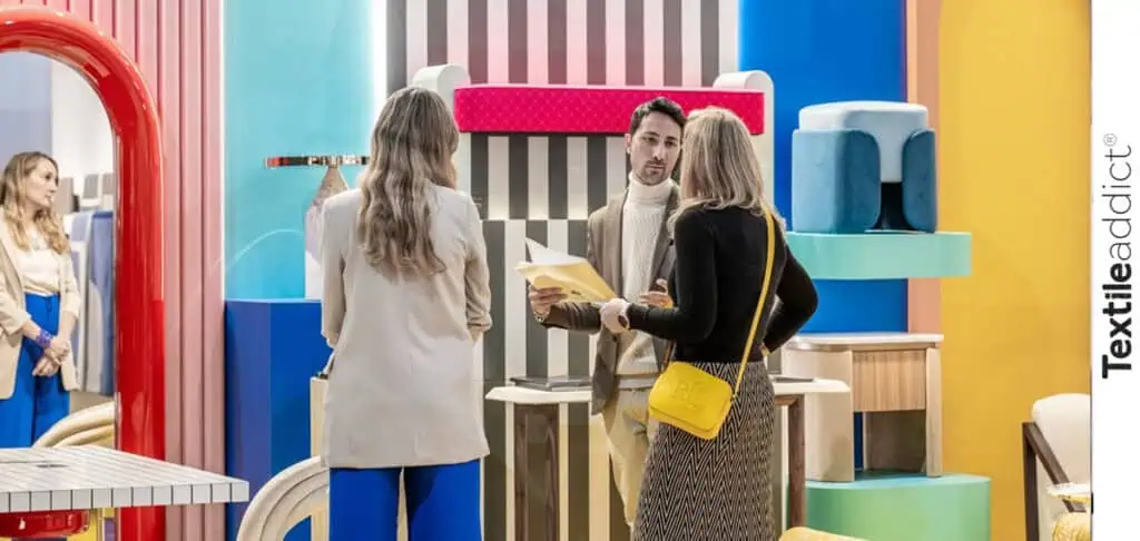 Un stand élégant de Maison & Objet, avec des tissus d’ameublement sophistiqués et des visiteurs en échange