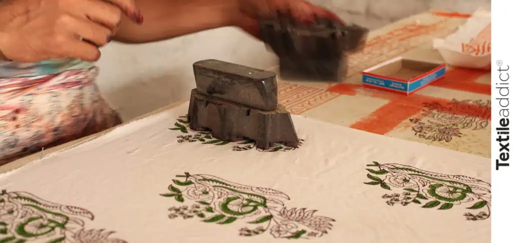 Artisan appliquant une impression au bloc de bois sur tissu, technique ancestrale de l’impression textile